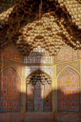 Fototapeta na wymiar Sunset shadows are cast over the intricate mosaic tiles and colorful stalactite moulding of an alcove at the Vakil Mosque in Shiraz, in the Fars province of southern Iran