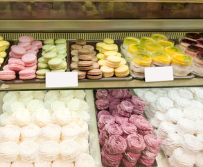 Assortment of Colorful macarons and meringue for sale in shop. sweets and cakes in candy shop, cafe showcase. Traditional french almond cakes pastry. Variety of flavours.