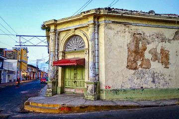 An old, weathered building with a green door and flaking paint on a corner in the city of Leon in northern Nicaragua