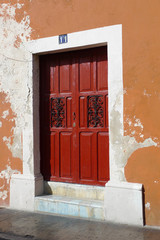 Fototapeta na wymiar Red Door on a rustic painted wall in Merida, Mexico