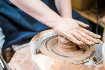 Professions Ideas. Closeup of Male Hands Working with Lump of Clay on Potter's Wheel in Workshop. Pressing it for Getting Form and Shape.