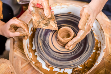 Closeup of Hands of  Male Potter Teaching His Female Apprentice to Work with Clay Lump on Potter's Wheel in Workshop.