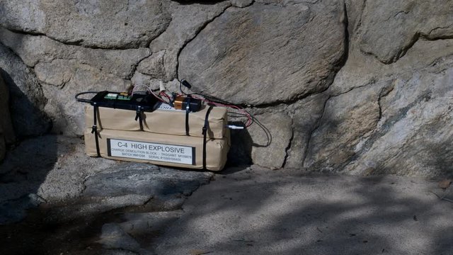 HIGH EXPLOSIVE BOMB SITTING AT THE BASE OF A STONE WALL.  4K ECU SLIDER PULL BACK SHOT.