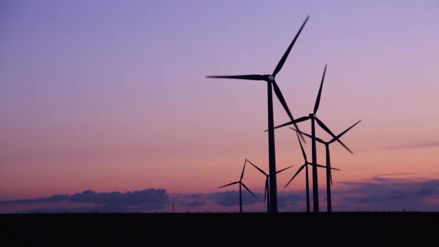 Close-up of silhouettes of wind turbines in the countryside under a beautiful sunset