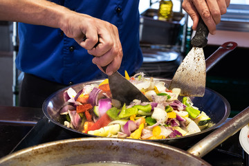 Frying food vegetables in cooking pan with spatulas.