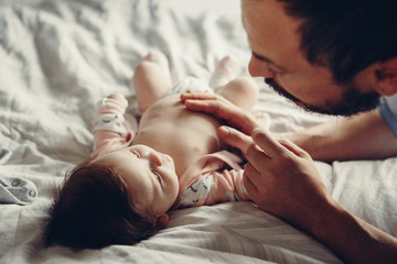 Portrait of middle age Caucasian father talking to newborn baby son daughter. Male man parent...