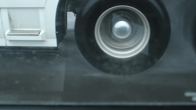 Passing commercial truck on rainy highway. Detail of wheels. View shot through passenger window. Ontario, Canada.