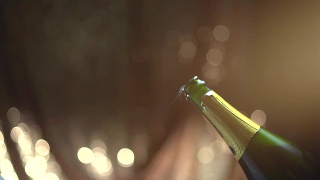 Champagne explosion. Sparkling wine popping, opening champagne bottle closeup. Sparkling wine over holiday blinking background. 4K UHD video footage. Slow motion 3840X2160