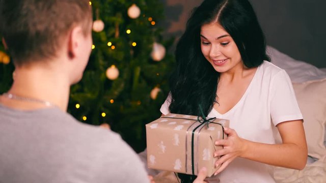Young crazy woman with decorated tree recieving a present and throwing it away. New year's eve