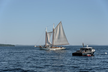 A Maine Lobster Boat Anchored Next to a Sailboat in a Bay in New England 