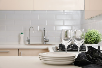 Stack of clean dishes and glasses on table in kitchen. Space for text