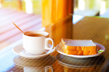 cup of coffee and dish of bread on the breakfast table in the morning