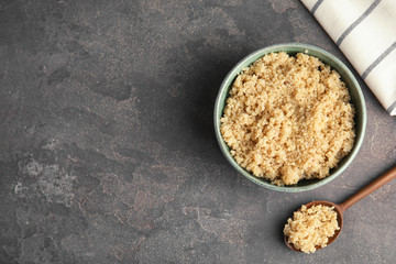Composition with cooked quinoa in bowl and wooden spoon on table, top view. Space for text
