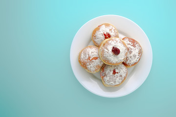 Tradition Jewish holiday sweets, donut sufganioyt with sugar powder and jam top view on blue background with copy space.