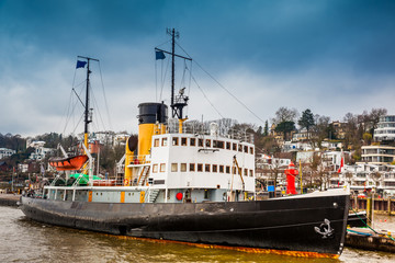Naklejka premium Ship and buildings on the banks of the Elbe River in Hamburg in a cold end of winter day