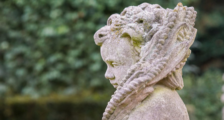 Stone angel statue in garden. Guardian angel statue in sunlight as a symbol of love in garden.