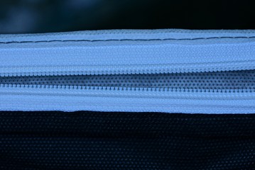 long white open zip on black fabric from a piece of clothing