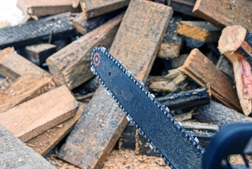 one chain saw in a pile of wooden firewood on a winter street in the snow