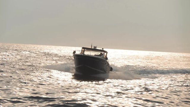 Modern motorboat moves fast on waves. Sea water reflects sunlight and shine