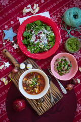 Happy Christmas food. Hot traditional beetroot, cabbage red soup - borsch for lunch or dinner with spinach cucumber salad and dip spread sauce. Red New Year background. Vegan and vegetarian