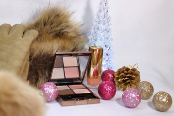 コスメ(アイシャドウとリップスティック)と腕時計と毛皮のストールと手袋とクリスマスツリーとピンクとゴールドの装飾(白背景)
