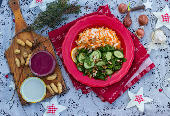 Winter Christmas or New Year fresh salad. Sauerkraut with carrot and cucumber spinach salad in one red plate.