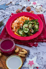 Winter Christmas or New Year fresh salad. Sauerkraut with carrot and cucumber spinach salad in one red plate.