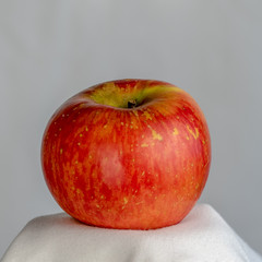 Close-up photograph of a fresh red apple with a grey background.