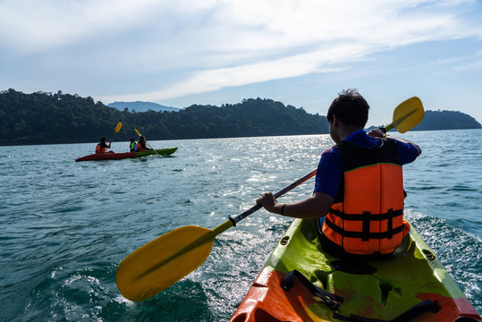 Asian teenagers and woman paddling on kayaks