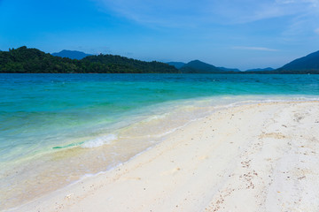 White sand beach and turquoise sea with mountain background