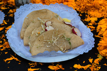 En la mesa del altar de muertos hay tres tacos.