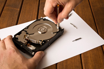 Obraz premium Hands of a man with a screwdriver disassembling the hard drive