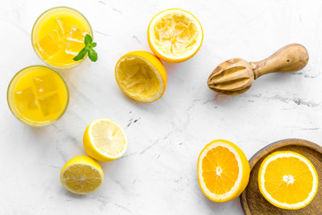 Squeeze fresh oranges with juicer. Orange juice in glass near half cut oranges on white stone background top view