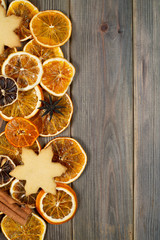 Dry slices of orange with cookie, star anise, cinnamon, on brown  wooden background, top view, vertical composition
