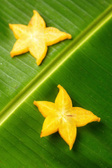 Slices of ripe yellow star fruit carambola or star apple ( starfruit ) on green banana leaf, vertical composition © 18042011