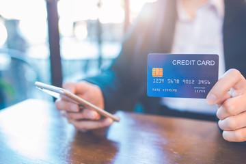 Business woman hand holds a blue credit card and use a cell phone in the office.