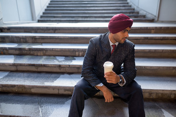 Portrait of Indian businessman sitting on stairs outdoors in city