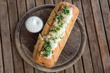 Tasty  garlic  bread, cheese and herbs on round wooden board on rustic table.Copy space for you text.Top view.