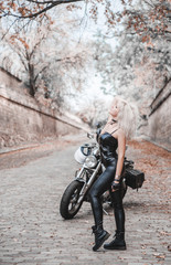 Fototapeta na wymiar Beautiful biker woman posing outdoor with motorcycle. 