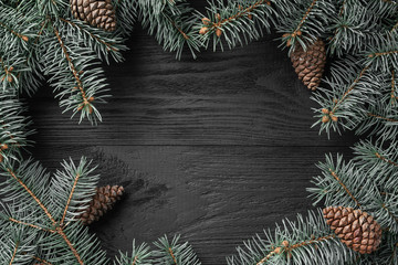 Christmas card with fir branches on a dark wooden rustic background, place for text. Xmas and happy new year greeting card. Top view, flat lay.
