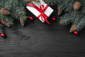 Christmas card with white gifts and fir branches on a dark wooden rustic background, place for text. Xmas and happy new year greeting card. Top view, flat lay.