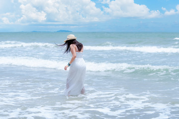 Fototapeta na wymiar Summer Holiday. Lifestyle woman white dress wearing fashion summer trips walking on the sandy ocean beach. Happy woman enjoy and relax vacation. Lifestyle and Travel Concept