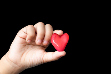 Fototapeta premium Isolated Hand holding a red candy shape heart on a black background.