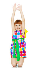 A little girl in a dress with a pattern from multi-colored circl