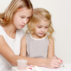 two girls paint on a piece of paper
