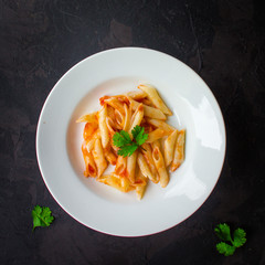 pasta, penne, tomato sauce and tomatoes. Vegan food.  (dark background). top view. copy space