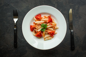 pasta, penne, tomato sauce and tomatoes. Vegan food.  (dark background). top view. copy space
