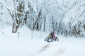 two persons ride quad bike in snowed forest © phpetrunina14