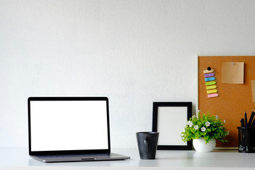 Mockup laptop computer on office table with office supplies.