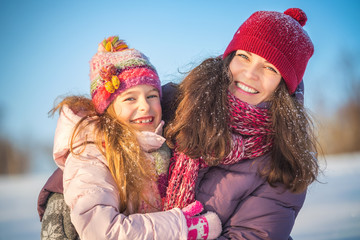 Fototapeta premium Little girl and her mother playing outdoors at sunny winter day